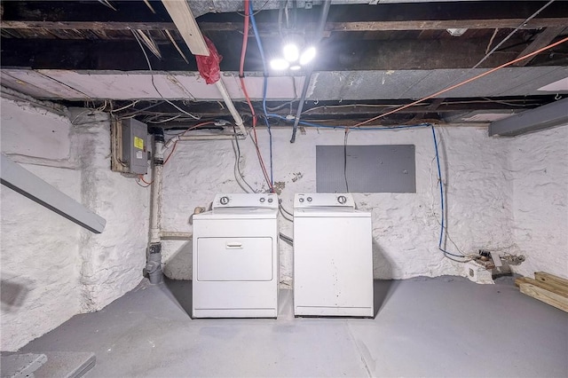 unfinished below grade area featuring electric panel and washer and clothes dryer