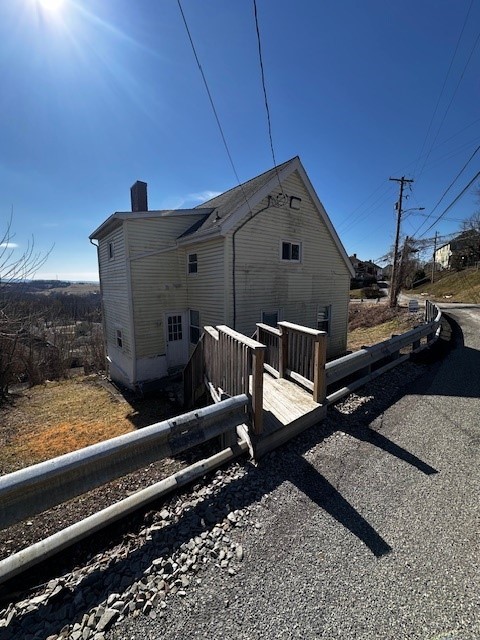 back of house featuring a wooden deck and a chimney