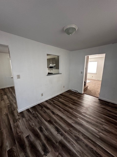 spare room with visible vents, a textured ceiling, dark wood-type flooring, and baseboards