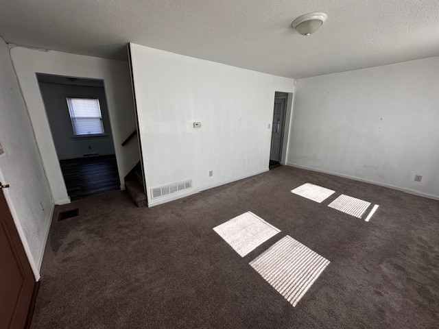 carpeted empty room featuring visible vents and a textured ceiling