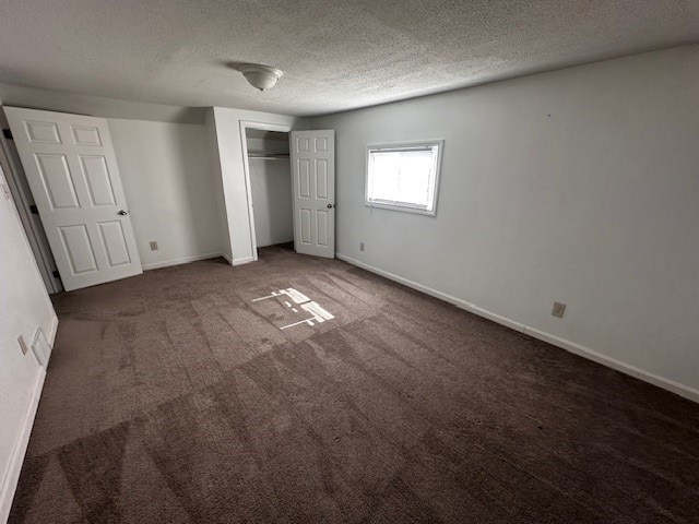 unfurnished bedroom featuring a closet, a textured ceiling, baseboards, and carpet