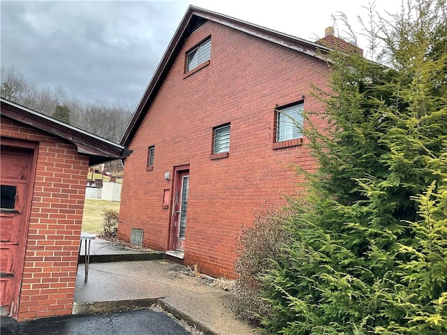 view of home's exterior with brick siding and a chimney