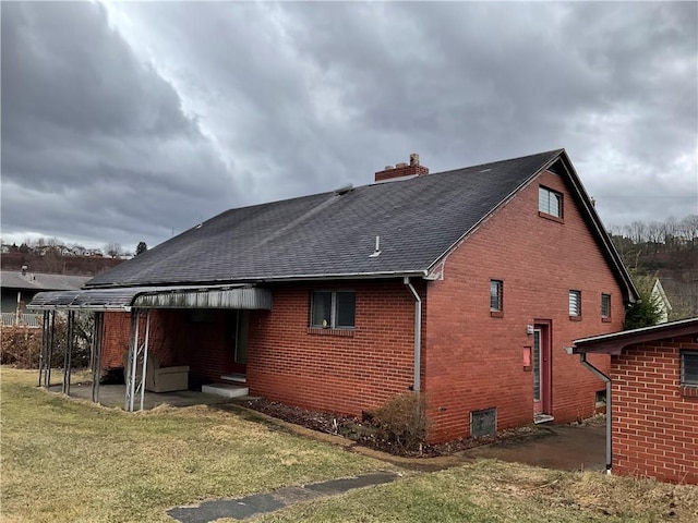 rear view of property featuring brick siding, a lawn, a chimney, and a shingled roof