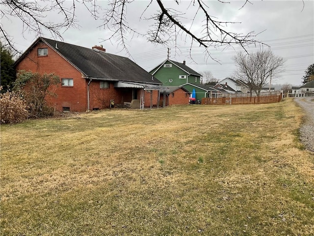 back of house featuring brick siding, fence, a chimney, a yard, and crawl space