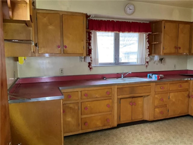 kitchen with brown cabinetry, light floors, open shelves, and a sink