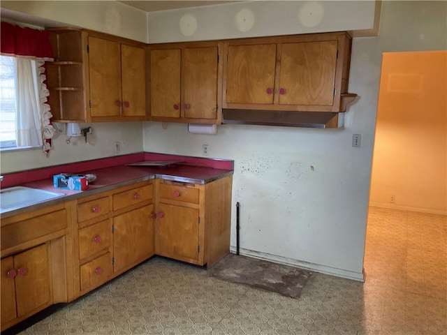 kitchen featuring a sink, light floors, brown cabinets, and open shelves