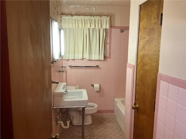 full bath with a sink, toilet, and tile walls