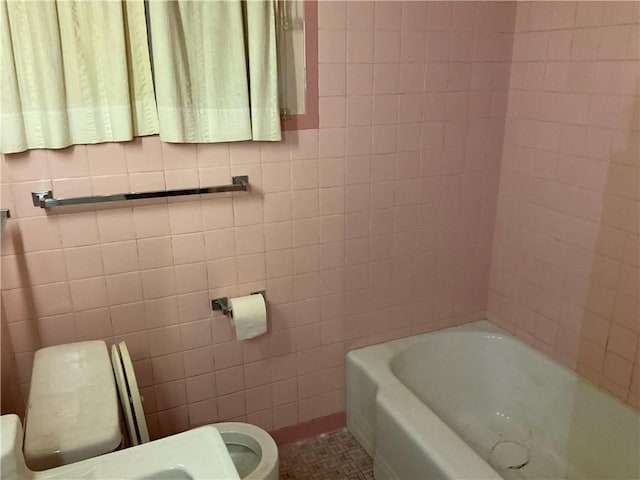 full bath featuring a bath, toilet, and tile walls