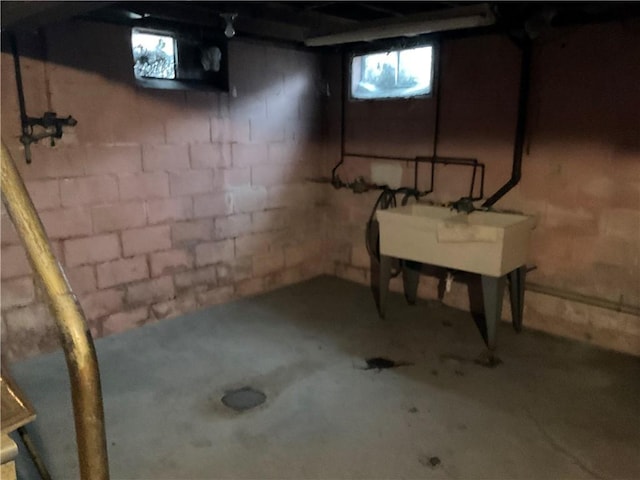 basement featuring concrete block wall and a sink