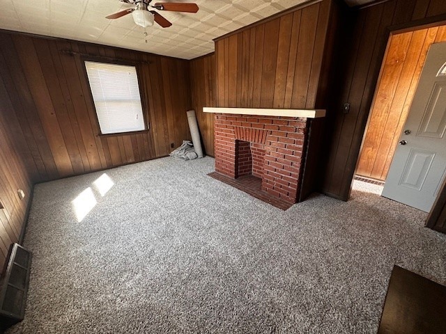 living area with carpet floors, wooden walls, ceiling fan, and a fireplace