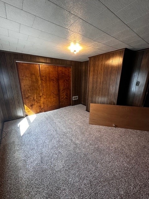 interior space featuring visible vents, carpet floors, and wooden walls