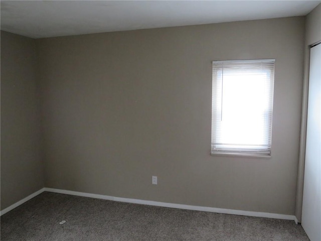 unfurnished room with baseboards and carpet flooring