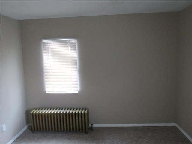 carpeted empty room with radiator and baseboards