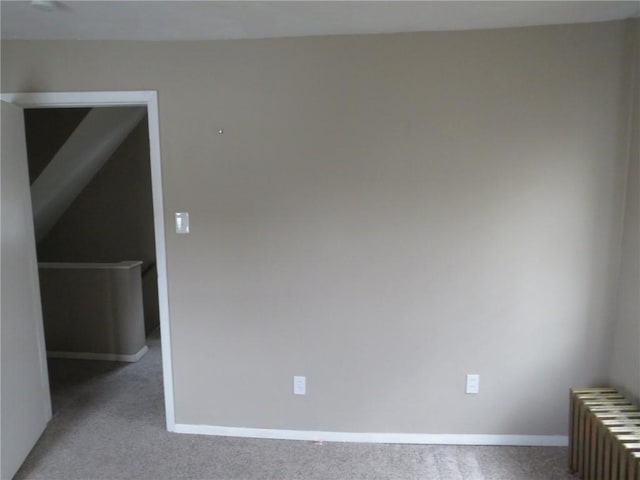 spare room with radiator, carpet, and baseboards