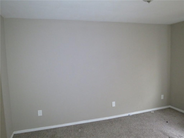 carpeted spare room featuring baseboards