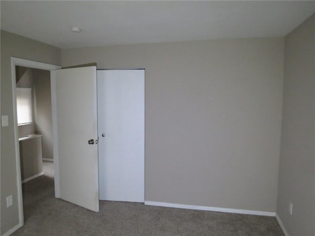 unfurnished bedroom with a closet, carpet flooring, and baseboards