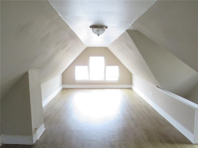 additional living space featuring baseboards, lofted ceiling, and wood finished floors