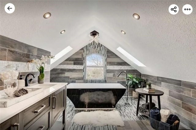 interior space with lofted ceiling with skylight, a soaking tub, and vanity