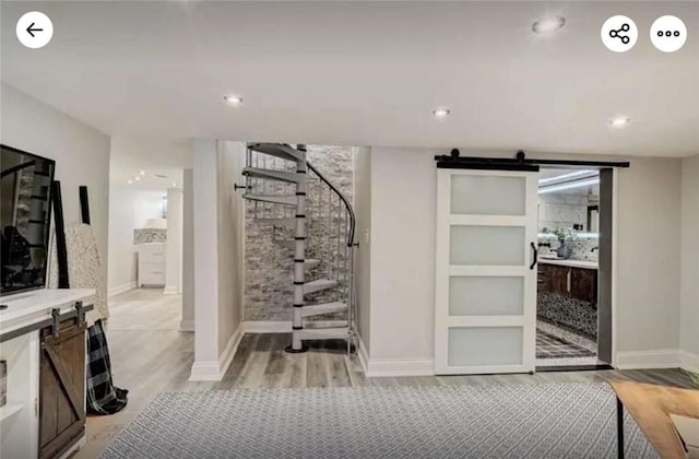 wine area featuring a barn door, light wood-style flooring, recessed lighting, and baseboards