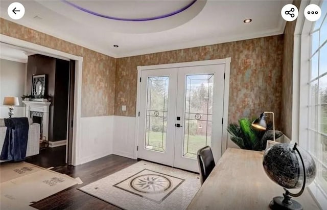 doorway to outside featuring wallpapered walls, a fireplace, dark wood-type flooring, french doors, and a raised ceiling