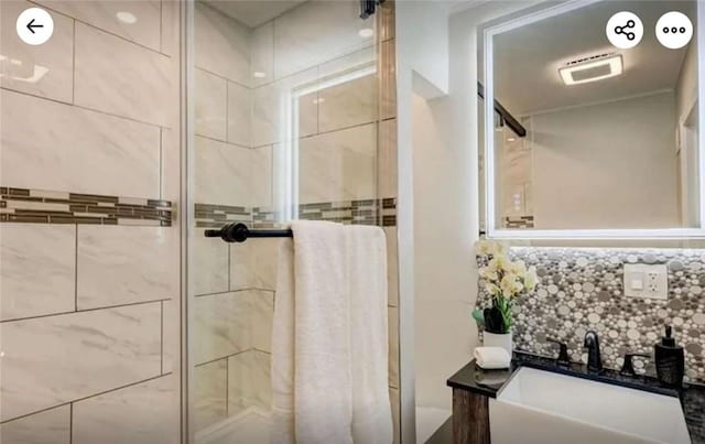 bathroom with decorative backsplash, a shower stall, and a sink