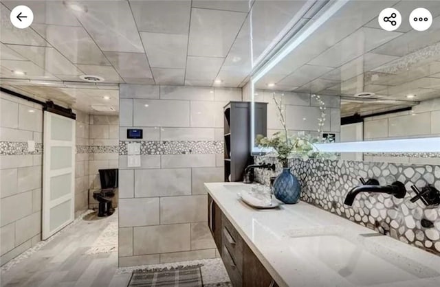 bathroom with double vanity, tile walls, and a sink