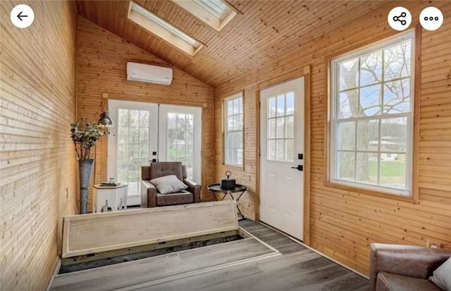 interior space with a wall mounted air conditioner, french doors, vaulted ceiling with skylight, and plenty of natural light