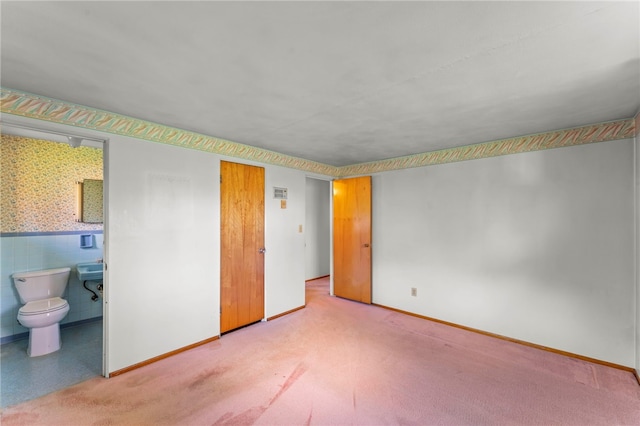 unfurnished bedroom featuring a wainscoted wall, baseboards, and connected bathroom