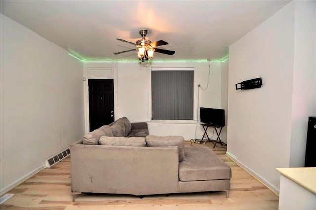 living area with visible vents, baseboards, light wood-type flooring, and a ceiling fan