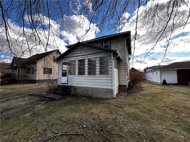 rear view of house with entry steps and a yard