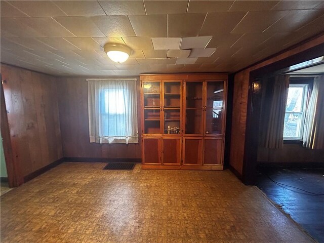 empty room featuring wooden walls and baseboards