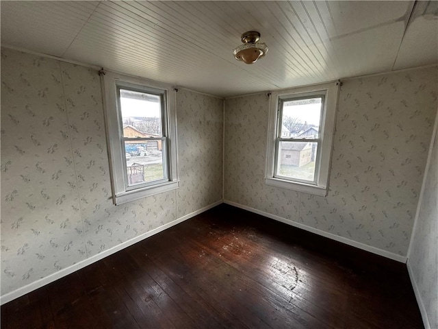 empty room featuring plenty of natural light, wallpapered walls, and dark wood-style flooring