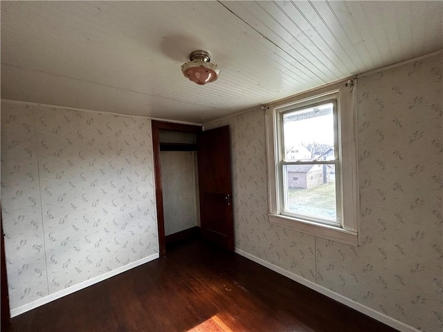 unfurnished room with baseboards, dark wood-style flooring, and wallpapered walls