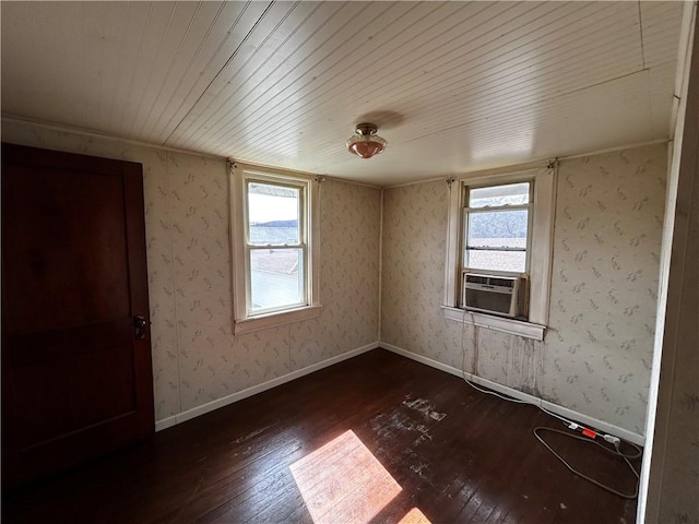 spare room with wallpapered walls, cooling unit, a healthy amount of sunlight, and dark wood-style flooring