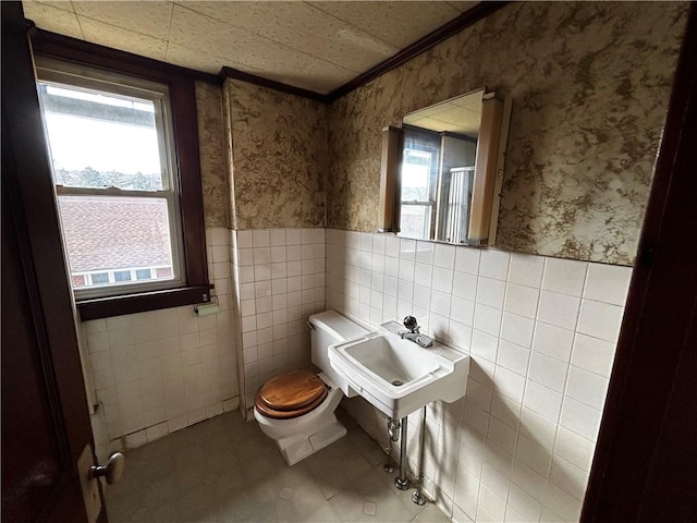 bathroom featuring a wainscoted wall, wallpapered walls, a sink, tile patterned floors, and toilet