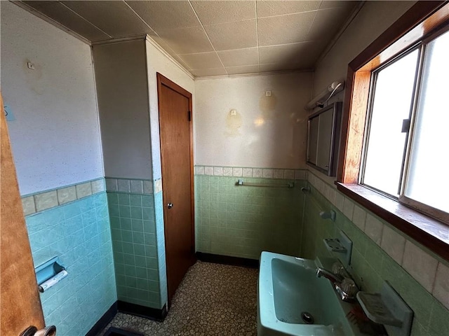 bathroom featuring a sink, tile walls, and wainscoting