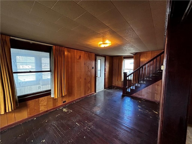 foyer entrance with stairway, baseboards, dark wood-type flooring, and wooden walls