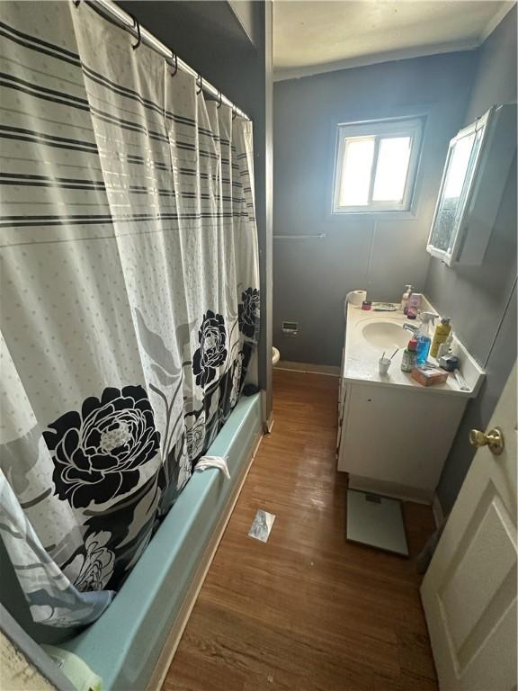 bathroom featuring shower / bathtub combination with curtain, toilet, wood finished floors, baseboards, and vanity