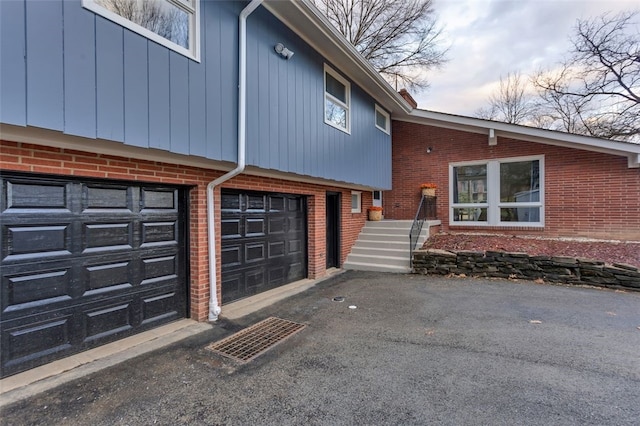 exterior space featuring aphalt driveway, brick siding, and an attached garage