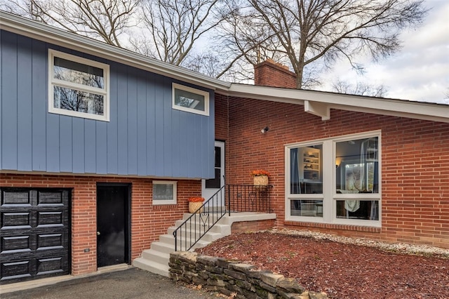 property entrance featuring brick siding, a garage, and a chimney