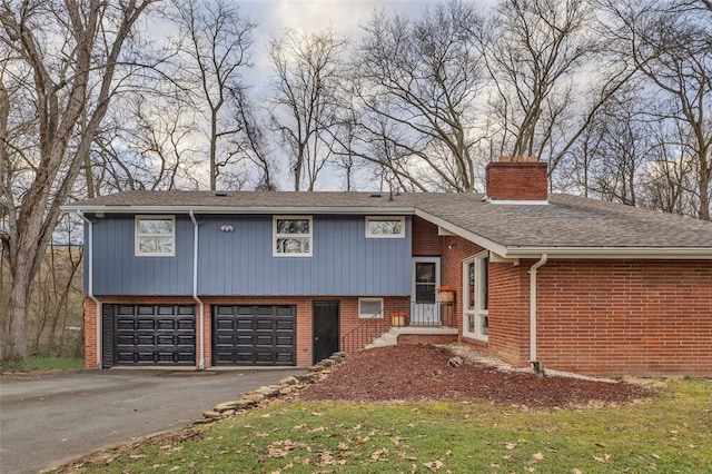 tri-level home with brick siding, a chimney, and a garage