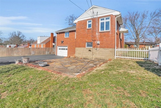 back of house featuring brick siding, a garage, a yard, and fence