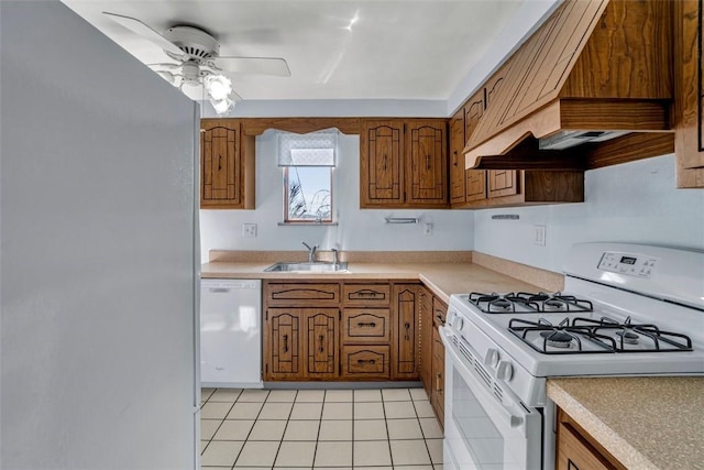 kitchen featuring brown cabinetry, white appliances, light countertops, and a sink