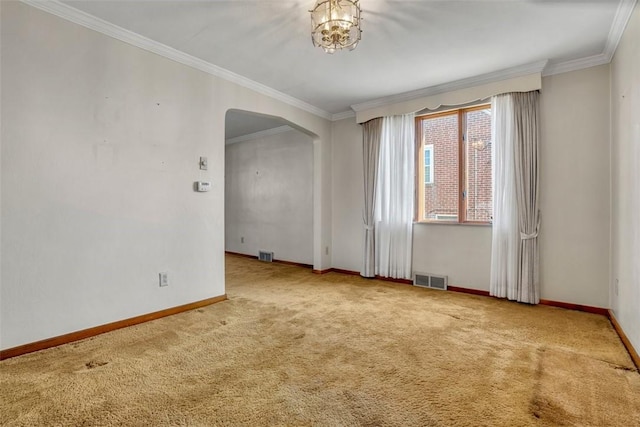 spare room with crown molding, carpet flooring, visible vents, and arched walkways