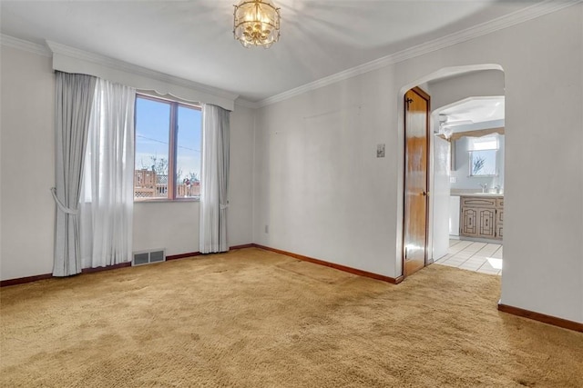 empty room featuring visible vents, arched walkways, carpet, and ornamental molding