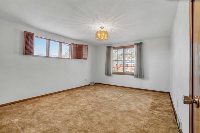 empty room with an inviting chandelier, carpet flooring, baseboards, and visible vents