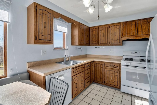 kitchen with white appliances, light countertops, brown cabinets, and a sink