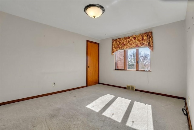 carpeted spare room featuring visible vents and baseboards