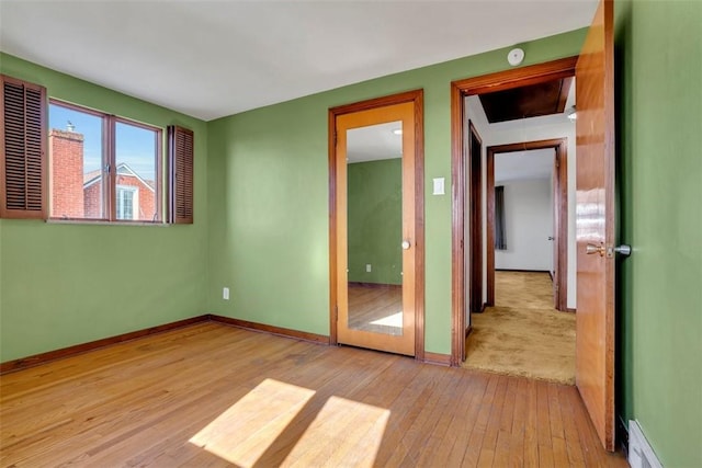 spare room featuring baseboard heating, visible vents, baseboards, and hardwood / wood-style floors