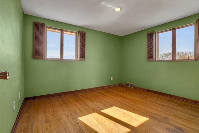 empty room with visible vents, baseboards, and hardwood / wood-style flooring